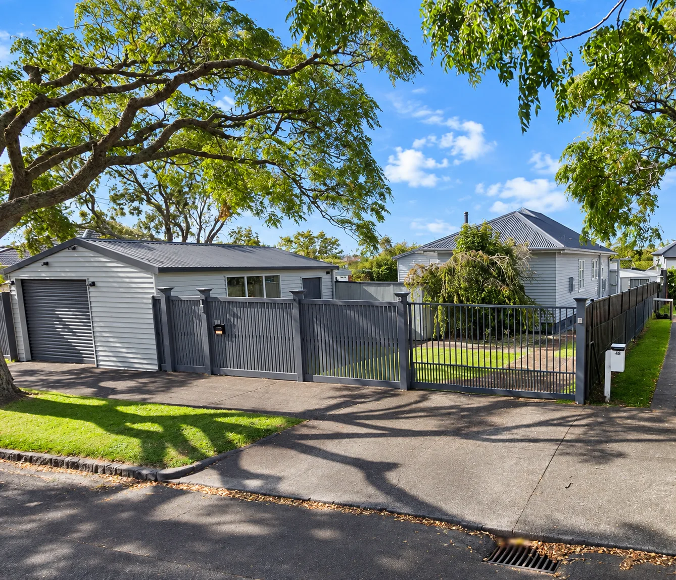 The original single-level weatherboard house with a separate garage and grey fence