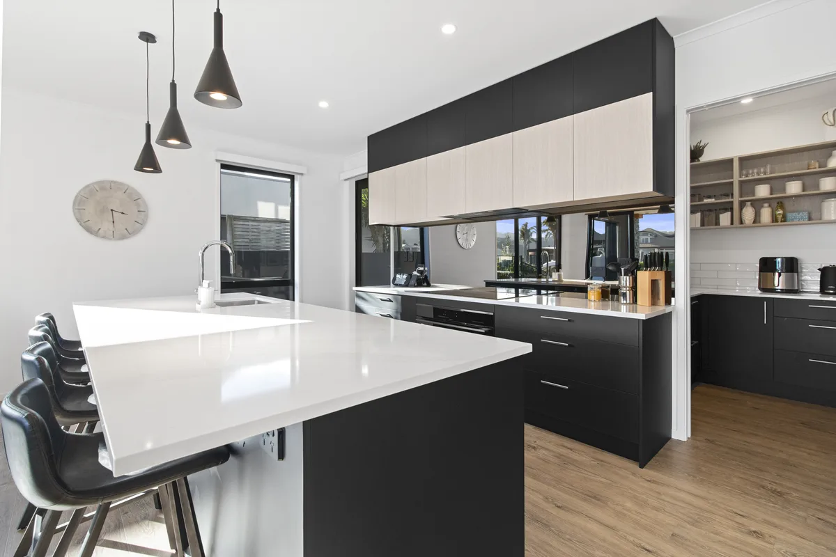 Kitchen with a white stone island, black cabinetry and a walk-in pantry
